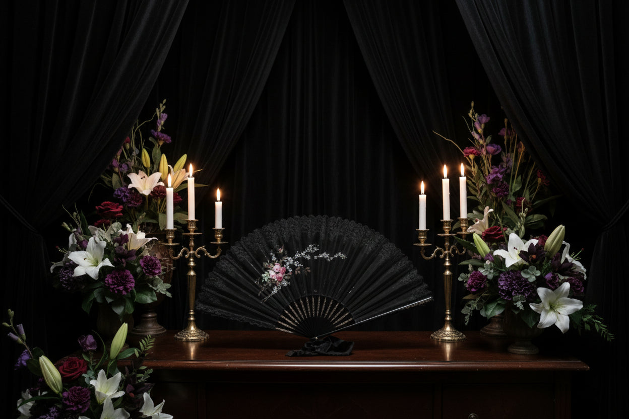 Decorative black fan with floral design on a white surface