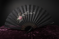 Antique Victorian black lace mourning fan displayed on dark velvet with dramatic lighting